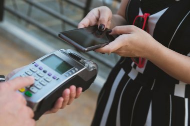 Kadın elektronik okuma ile mobil ödeme yapmak için akıllı telefon kullanıyor