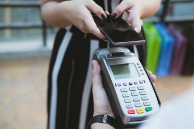 Kadın elektronik okuma ile mobil ödeme yapmak için akıllı telefon kullanıyor