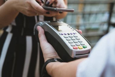 Kadın elektronik okuma ile mobil ödeme yapmak için akıllı telefon kullanıyor