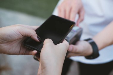 Kadın elektronik okuma ile mobil ödeme yapmak için akıllı telefon kullanıyor