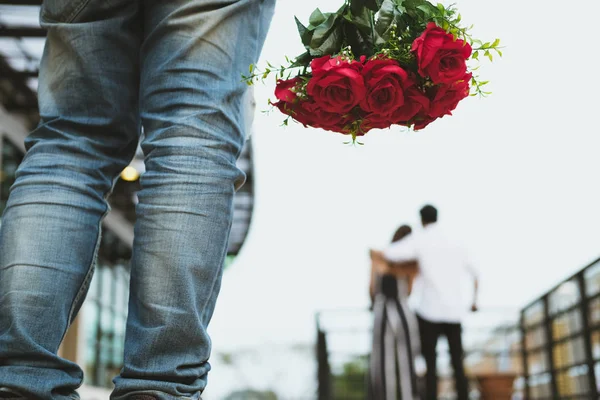 Kalbi kırık adam tutarak s üzgün kırmızı gül buketi