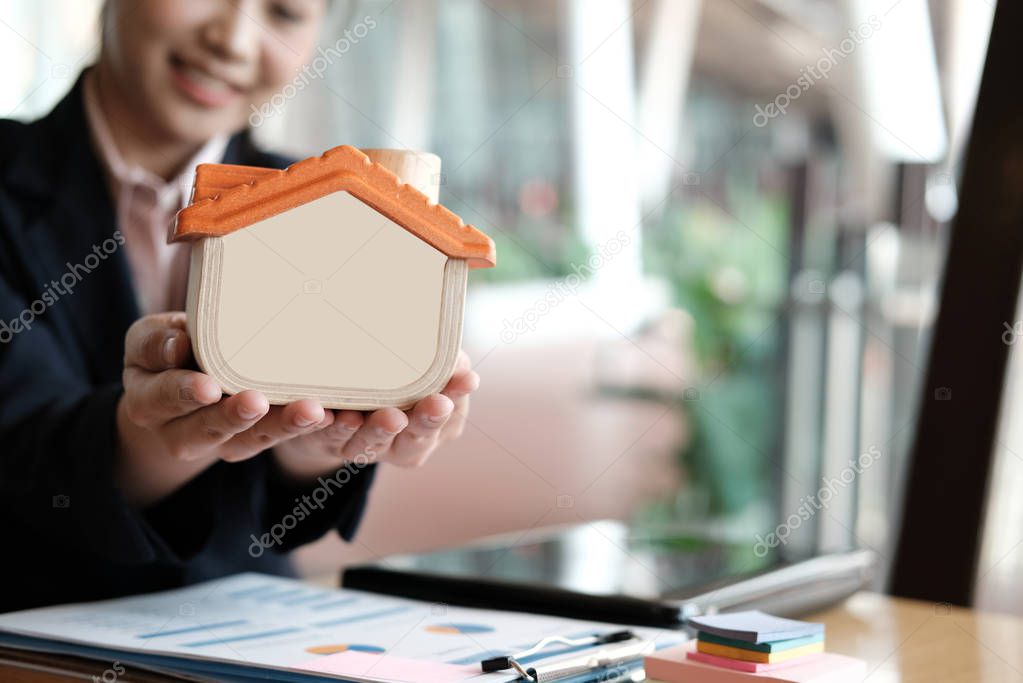 realtor holding house model at office. real estate agent showing