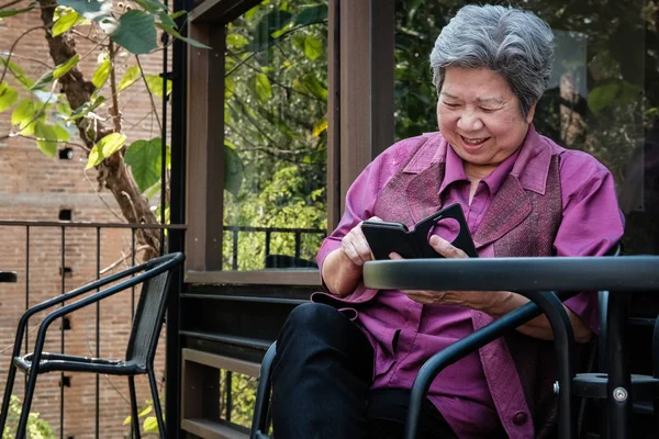 Elder woman holding mobile phone on terrace. elderly female text — Stock Photo, Image