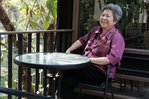 Γέρων γυναίκα στηρίζεται σε βεράντα. ηλικιωμένους θηλυκό χαλάρωσης στο patio — Φωτογραφία Αρχείου