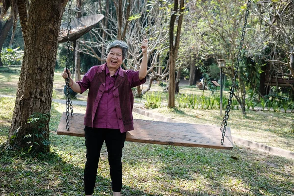 엘 더 여자 정원에서 휴식입니다. 노인 여성 스윙에 편안한 — 스톡 사진