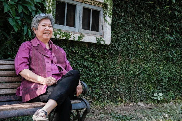 Femeia mai în vârstă se odihneşte în grădină. Femeia în vârstă care se relaxează în parc . — Fotografie, imagine de stoc