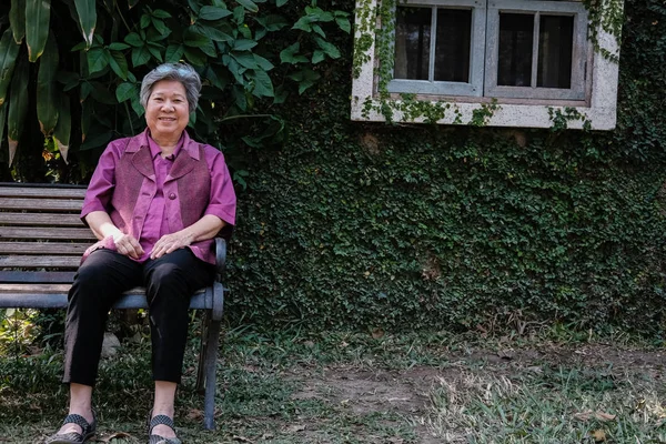 Una anciana descansando en el jardín. anciana mujer relajándose en parque . — Foto de Stock