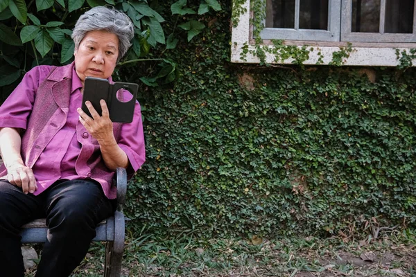 Anciana sosteniendo teléfono móvil en el jardín. texti femenino de edad avanzada — Foto de Stock