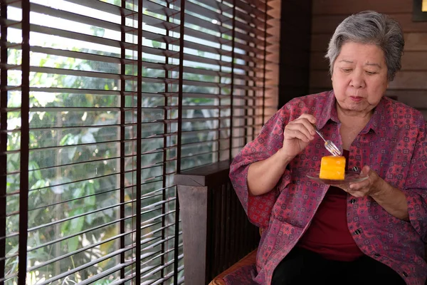 老年老人在咖啡馆吃橙饼。亚洲老年妇女坐 — 图库照片