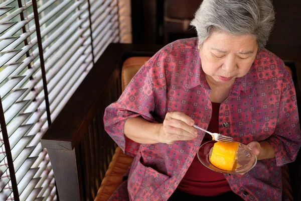 Mayores comiendo pastel de naranja en la cafetería. asiático anciano mujer sentarse — Foto de Stock