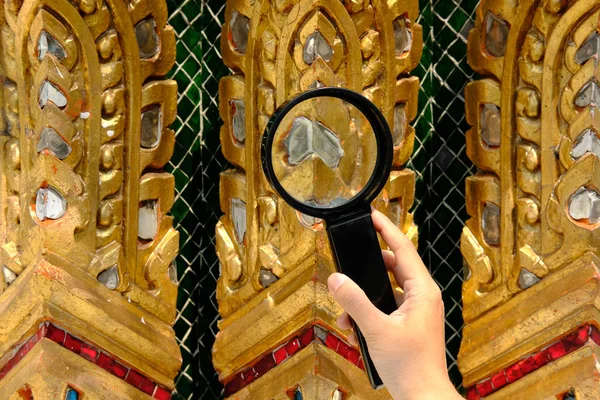 Woman use magnifying glass to look at temple wall encrusted with — Stock Photo, Image