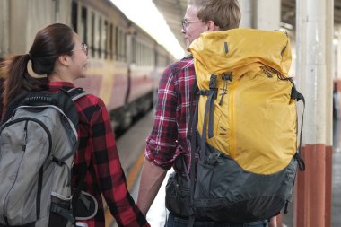adam ve kadın, elele sırt çantası ile tren istasyonu. sevgi dolu