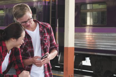 adam ve kadın smartphone cep telefonu ile tren istasyonunda app kullanın. Gezgin cou