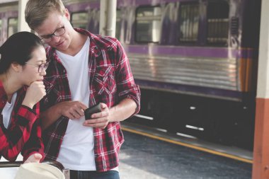 adam ve kadın smartphone cep telefonu ile tren istasyonunda app kullanın. Gezgin cou