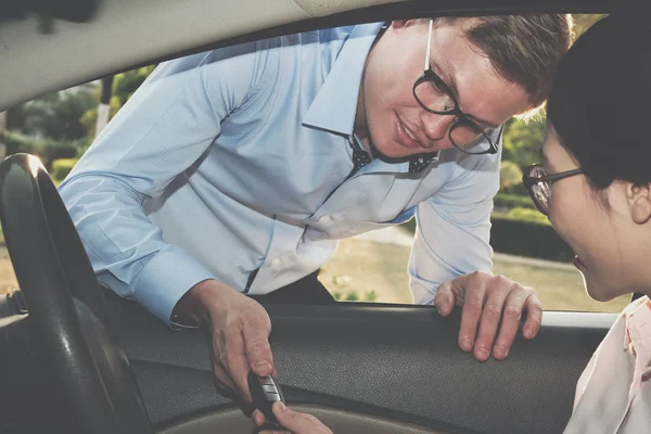セールスマンは、顧客に車のキーを与えます。女性のディーラーからの購入車. — ストック写真