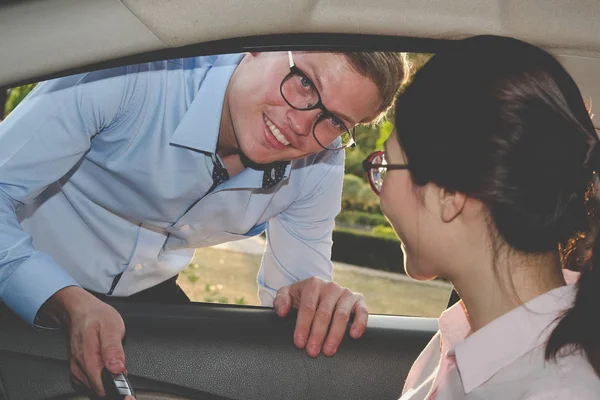 Satıcı müşteri için arabanın anahtarını ver. Satıcı kadın satın alma arabadan.