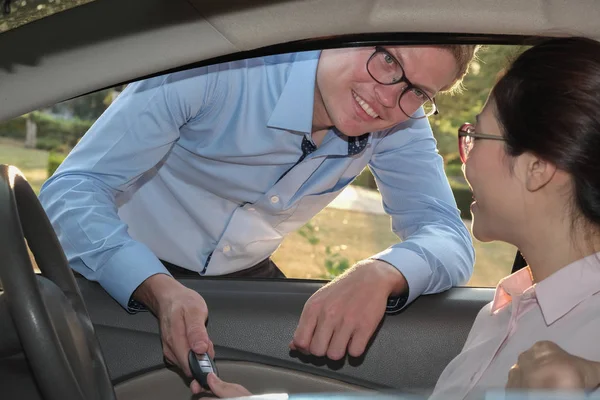 Satıcı müşteri için arabanın anahtarını ver. Satıcı kadın satın alma arabadan.