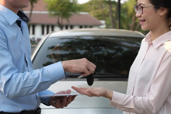 Vendedor dar la llave del coche al cliente. mujer comprando coche de distribuidor . — Foto de Stock