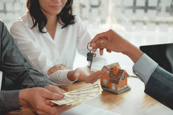 Emlakçı çift müşteriye evin anahtarını veriyor. istemci ödemesi