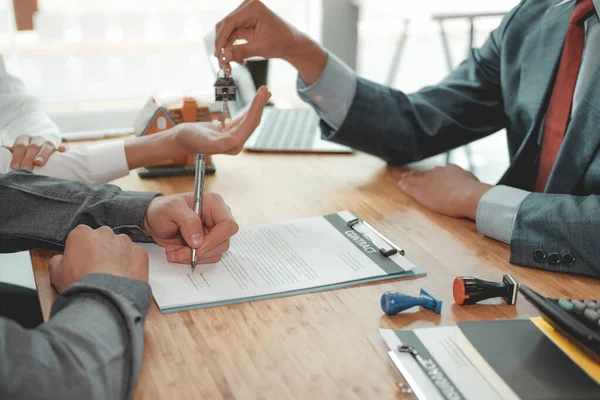 Agente de bienes raíces dar llave de la casa para pareja cliente. firma del cliente — Foto de Stock