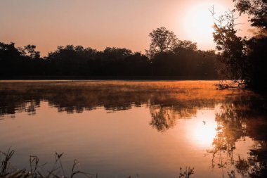 Göl kenarında dağ manzaralı sabah güneşi & sisi. 
