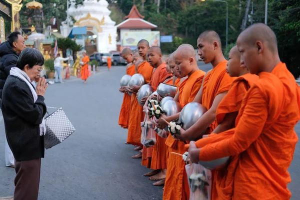 Люди, дающие пищу буддистскому монаху — стоковое фото