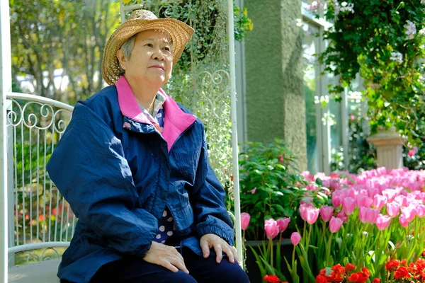 Стара літня жінка відпочиває в саду. літня жінка розслабляється на відкритому повітрі — стокове фото