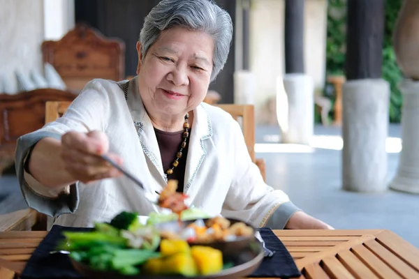 Old elderly senior elder woman eating food. mature retirement li Stock Photo
