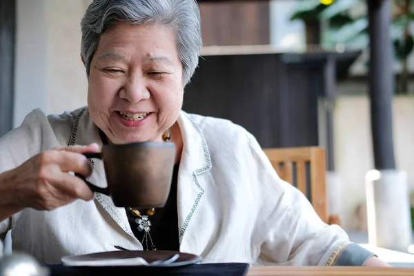 Old elderly senior elder woman drinking coffee tea. mature retir Stock Picture