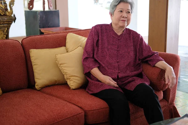 Old elderly senior elder woman resting relaxing on sofa couch in — 图库照片