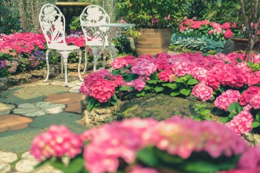 Baharda çiçek bahçesinde beyaz metal koltuk sandalyesi