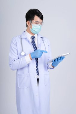 Doktor doktor doktor maske takıyor ve beyaz arka planda tablet ve steteskop var. Tıbbi profesyonel tıp sağlık hizmeti kavramı