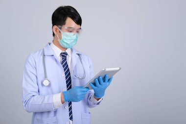 Doktor doktor doktor maske takıyor ve beyaz arka planda tablet ve steteskop var. Tıbbi profesyonel tıp sağlık hizmeti kavramı