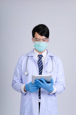 Doktor doktor doktor maske takıyor ve beyaz arka planda tablet ve steteskop var. Tıbbi profesyonel tıp sağlık hizmeti kavramı
