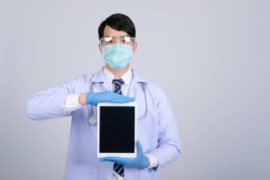 Doktor doktor doktor maske takıyor ve beyaz arka planda tablet ve steteskop var. Tıbbi profesyonel tıp sağlık hizmeti kavramı