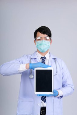 Doktor doktor doktor maske takıyor ve beyaz arka planda tablet ve steteskop var. Tıbbi profesyonel tıp sağlık hizmeti kavramı