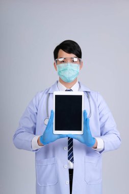Doktor doktor doktor maske takıyor ve beyaz arka planda tablet ve steteskop var. Tıbbi profesyonel tıp sağlık hizmeti kavramı