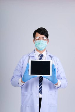 Doktor doktor doktor maske takıyor ve beyaz arka planda tablet ve steteskop var. Tıbbi profesyonel tıp sağlık hizmeti kavramı