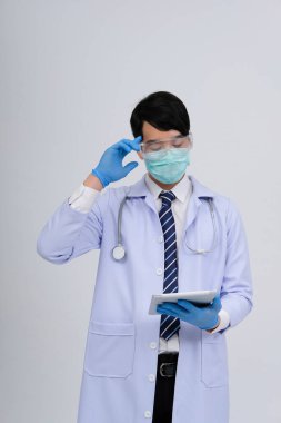 Doktor doktor doktor maske takıyor ve beyaz arka planda tablet ve steteskop var. Tıbbi profesyonel tıp sağlık hizmeti kavramı