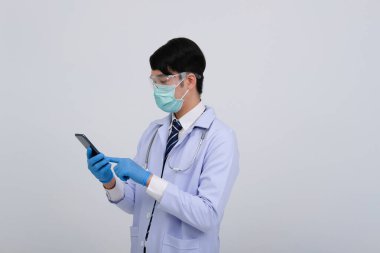 Doktor doktor doktor, maske takıyor ve beyaz arka planda akıllı telefon ve steteskop var. Tıbbi profesyonel tıp sağlık hizmeti kavramı