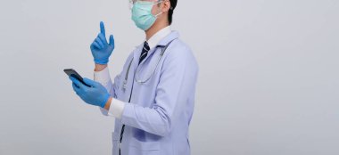 Doktor doktor doktor, maske takıyor ve beyaz arka planda akıllı telefon ve steteskop var. Tıbbi profesyonel tıp sağlık hizmeti kavramı