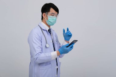Doktor doktor doktor, maske takıyor ve beyaz arka planda akıllı telefon ve steteskop var. Tıbbi profesyonel tıp sağlık hizmeti kavramı