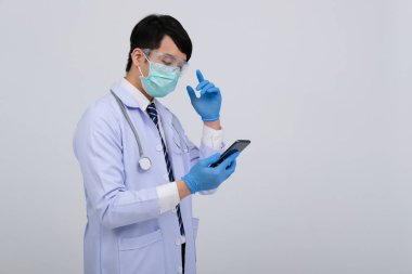 Doktor doktor doktor, maske takıyor ve beyaz arka planda akıllı telefon ve steteskop var. Tıbbi profesyonel tıp sağlık hizmeti kavramı