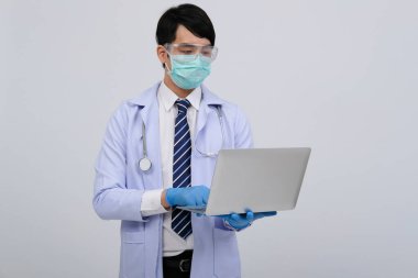 Doktor doktor doktor maske takıyor ve beyaz arka planda bilgisayar ve steteskop var. Tıbbi profesyonel tıp sağlık hizmeti kavramı