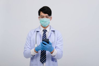 Doktor doktor doktor, maske takıyor ve beyaz arka planda akıllı telefon ve steteskop var. Tıbbi profesyonel tıp sağlık hizmeti kavramı