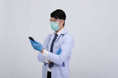 Doktor doktor doktor, maske takıyor ve beyaz arka planda akıllı telefon ve steteskop var. Tıbbi profesyonel tıp sağlık hizmeti kavramı