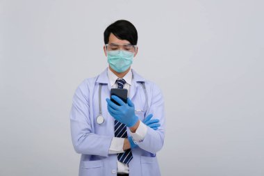 Doktor doktor doktor, maske takıyor ve beyaz arka planda akıllı telefon ve steteskop var. Tıbbi profesyonel tıp sağlık hizmeti kavramı