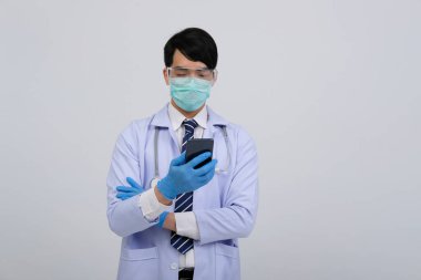 Doktor doktor doktor, maske takıyor ve beyaz arka planda akıllı telefon ve steteskop var. Tıbbi profesyonel tıp sağlık hizmeti kavramı