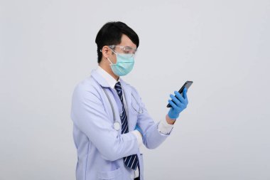 Doktor doktor doktor, maske takıyor ve beyaz arka planda akıllı telefon ve steteskop var. Tıbbi profesyonel tıp sağlık hizmeti kavramı