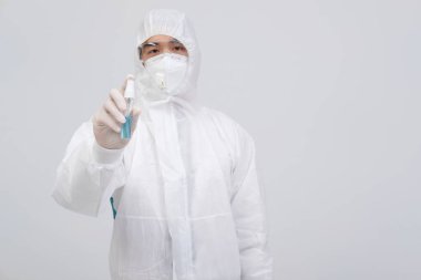 Biyolojik koruyucu üniforma, maske giyen adam doktor. Virüs bakterilerini dezenfekte etmek için el alkolü dezenfektanlı eldivenler.